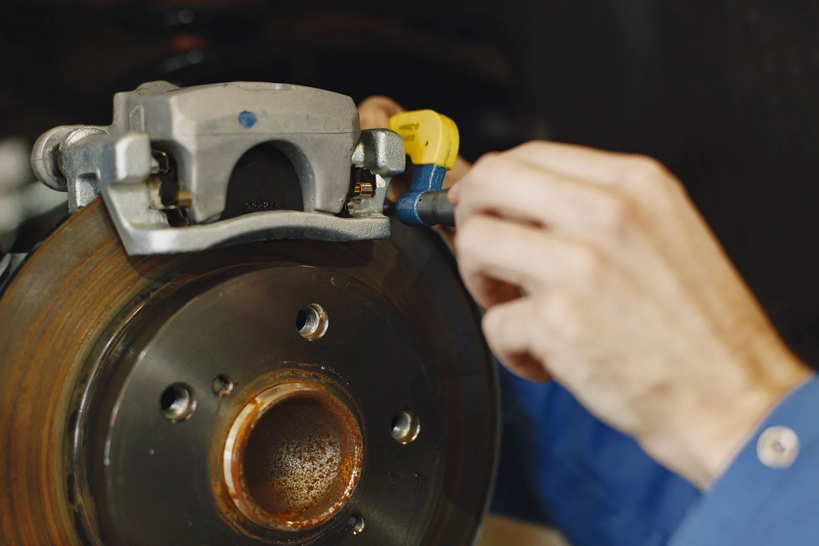 Illustrative stock photograph of a vehicle disc brake being inspected