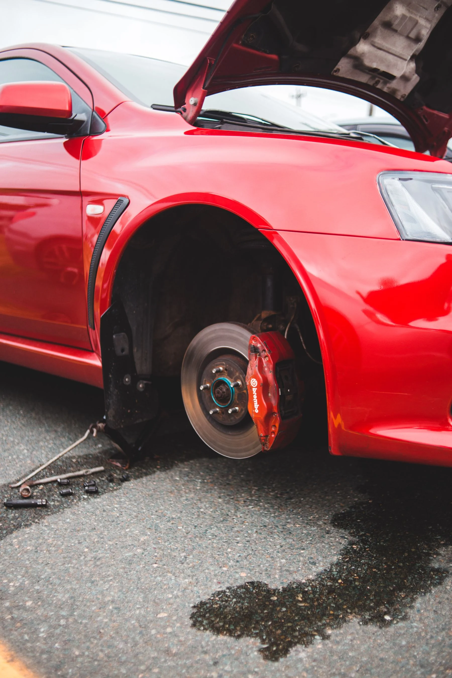 Illustrative stock photograph of a car outdoors with its wheel removed, exposing the brake rotor