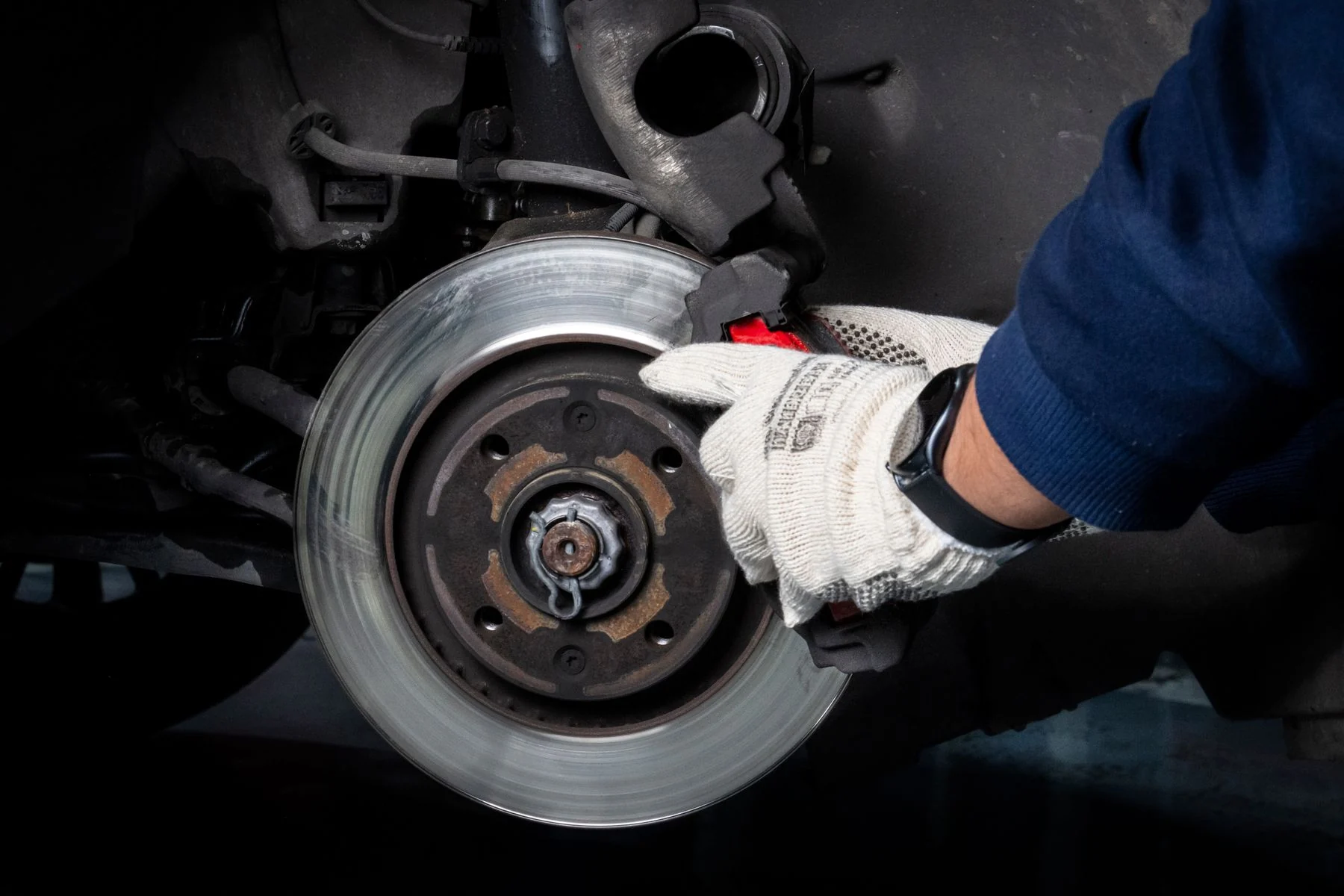 Stock photograph of a mechanic working on a vehicle brake rotor and caliper