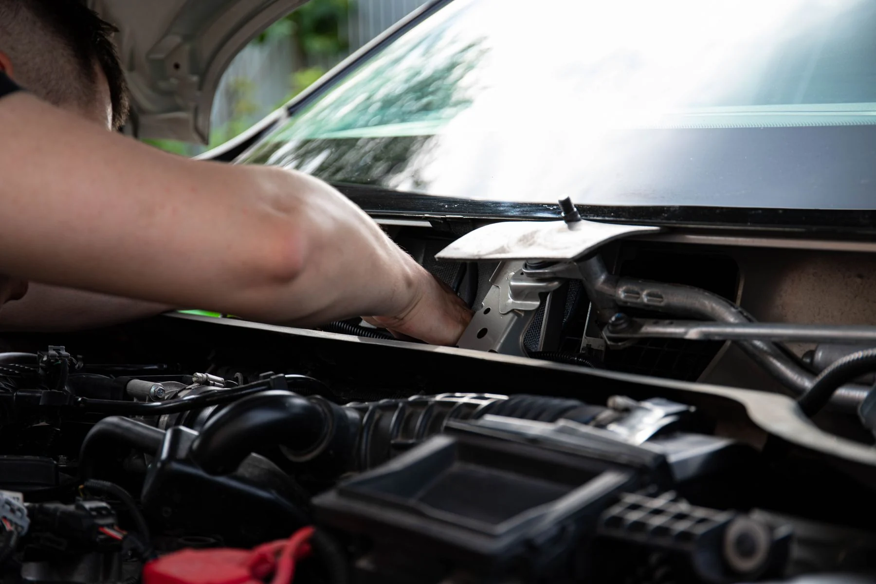Illustrative stock photograph of automotive service under a vehicle hood outdoors