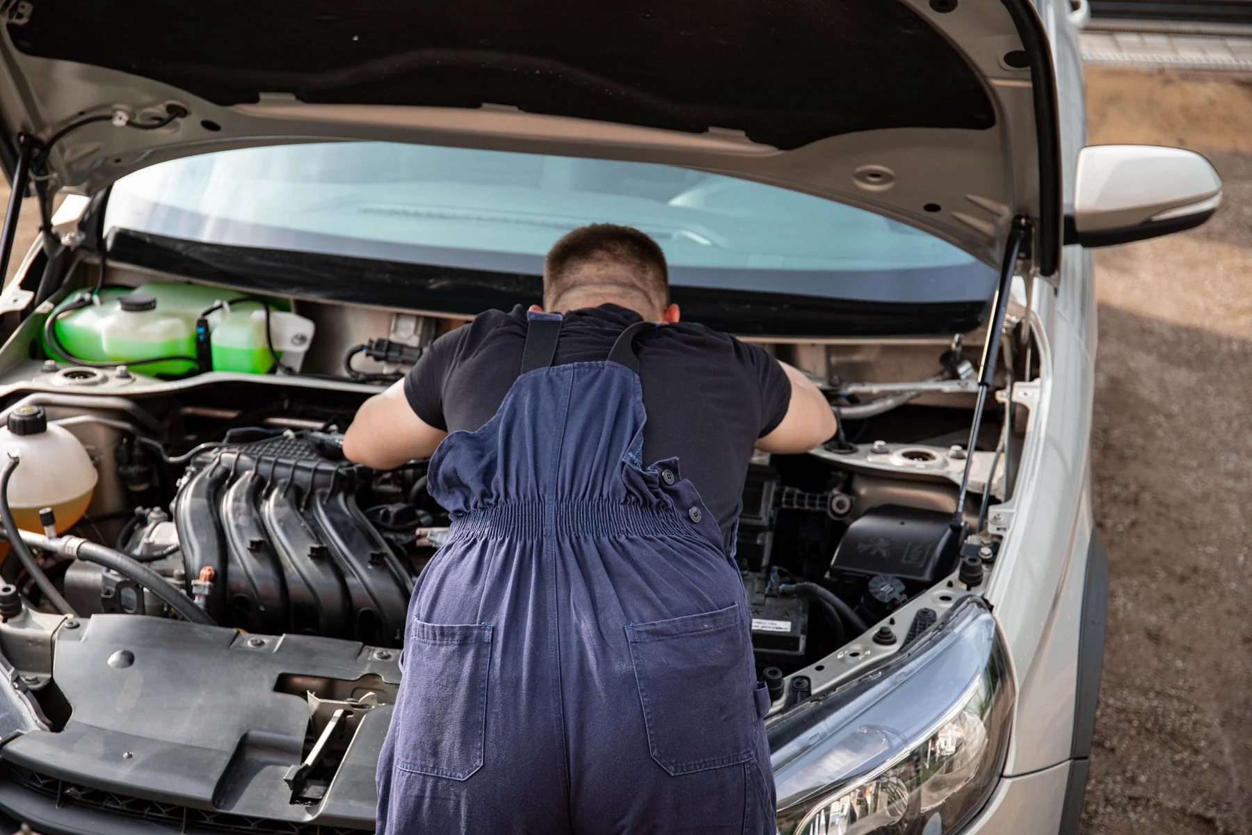 Illustrative stock photograph showing on-location automotive service under a vehicle hood