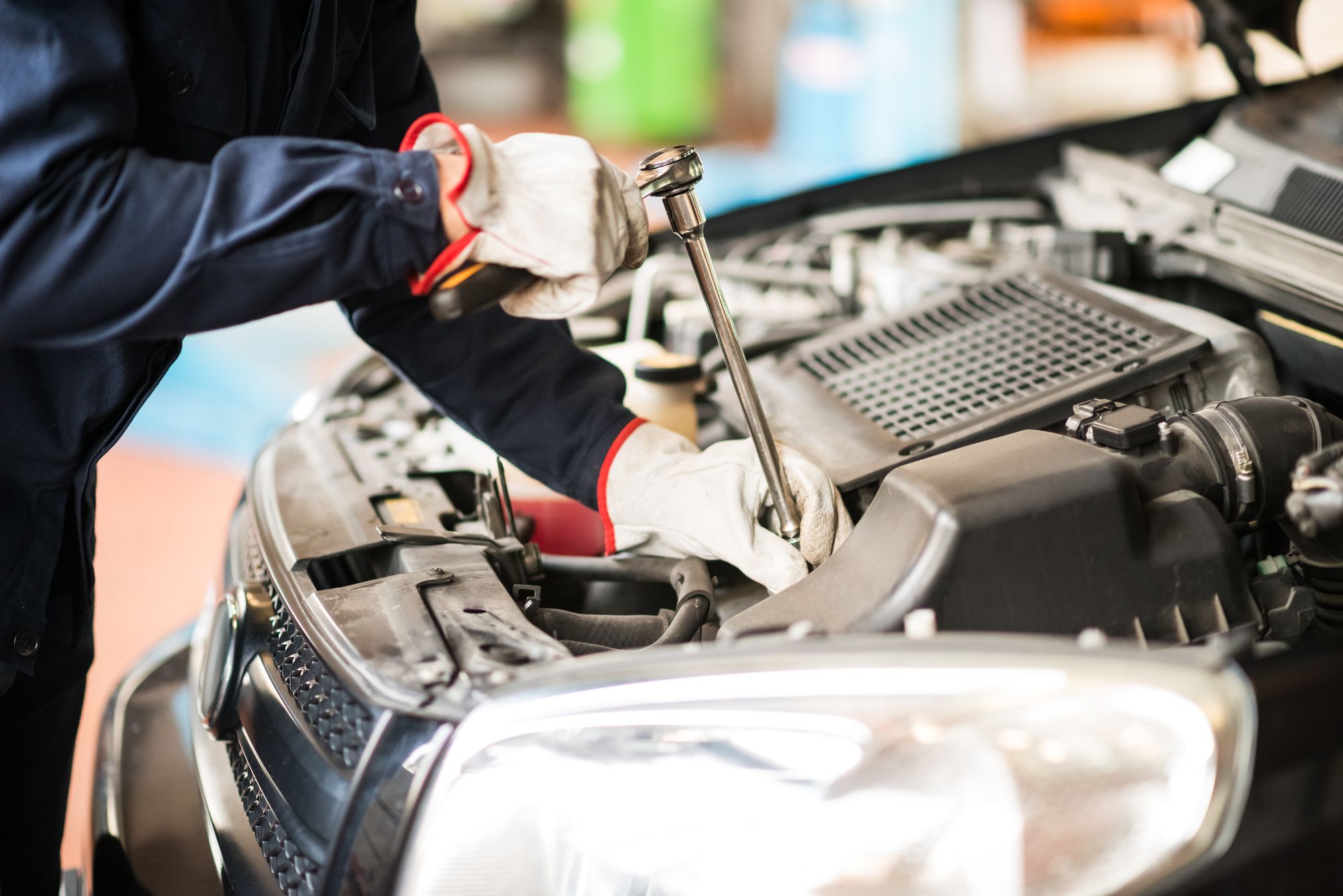 Illustrative photograph of a professional performing passenger vehicle engine-bay maintenance